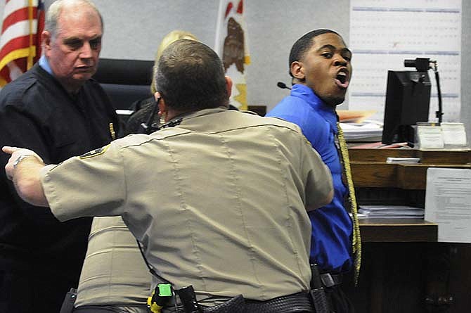 In this photo taken on Feb. 27, 2015, Kamron T. Taylor, right, is removed from a Kankakee County courtroom in Kankakee, Ill., by a bailiff and two sheriff's deputies, after struggling with the deputies and yelling at the crowd in the gallery after being found guilty of murder. Early Wednesday morning, April 1, 2015. Taylor escaped from the Jerome Combs Detention Center in Kankakee after overpowering a guard and taking his keys, uniform and SUV. 