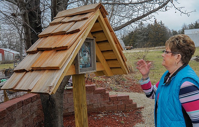 Lorraine Smith looks at one of the 14 Stations of the Cross installed in her backyard garden this winter, where she lifts up prayers and intercession daily.