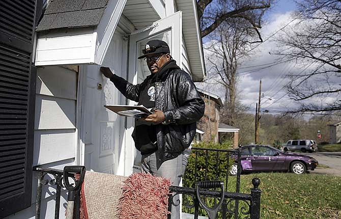 In this April 3, 2015 photo, Reginald Rounds, a volunteer with the Organization for Black Struggle, knocks on a door while canvassing a neighborhood in Ferguson, Mo. The city is preparing for an election on Tuesday when three of six city council seats will be decided.