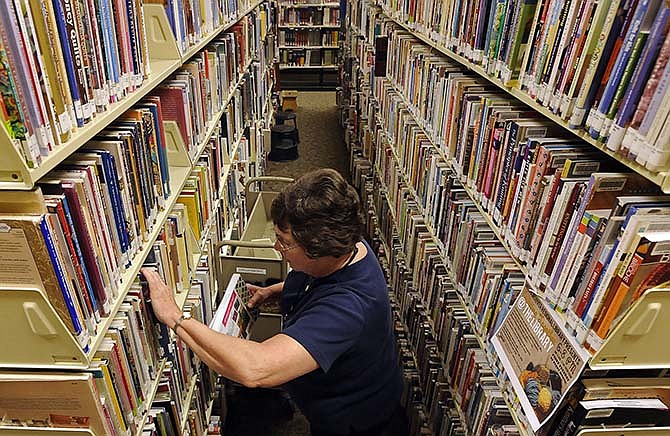 Librarian Janet Bowles looks through the call numbers in the nonfiction arts and crafts section while carefully reshelving a number of returned books at the Missouri River Regional Library in Jefferson City.