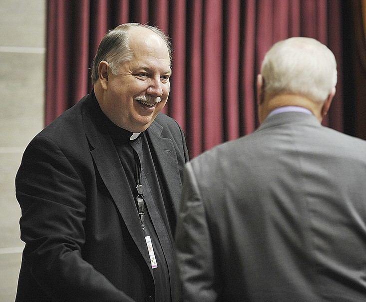 Msgr. Robert Kurwicki visits with a legislator before the start of a House session.