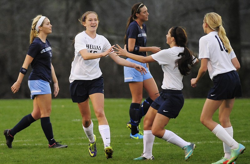 Helias players rush to celebrate with Kayla Yanskey after she caught the St. Dominic goalkeeper off her line and chipped it over her head for the game-tying goal in the second half of Monday's game at the 179 Soccer Park.