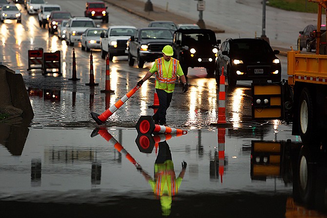 A Missouri Department of Transportation worker adjusts cones on a flooded section of south bound Route 141 underneath Interstate 44 after a storm flooded the area on Tuesday, April 7, 2015, near Valley Park.