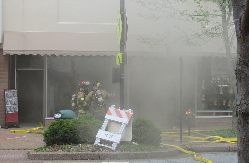 Smoke fills the street and nearby stores as the Jefferson City firefighters battle a Sunday afternoon blaze at Hair Plaza, 123 E. High St. JCFD spokesman Jason Turner said the fire started on a counter in back of the business, and had possibly been burning for awhile. 
