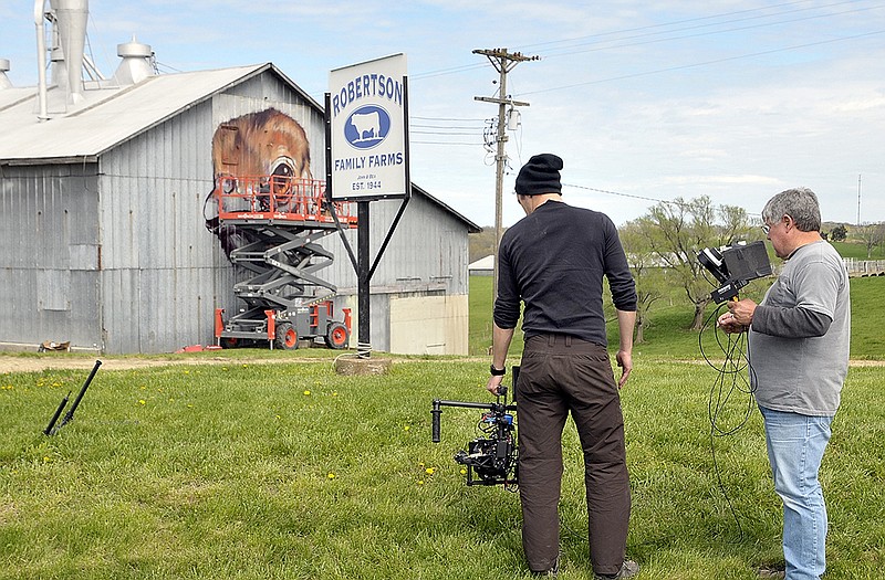 While painters are busy creating a mural on the Robertson Farm barn, a movie crew is busy documenting the process. Cameraman Greg Hardes and MoVi operator, Matt Trub, film a segment while Telmo Pieper and Miel Krutzmaan are on the lift using spray paint to fill in the outline they created Monday.