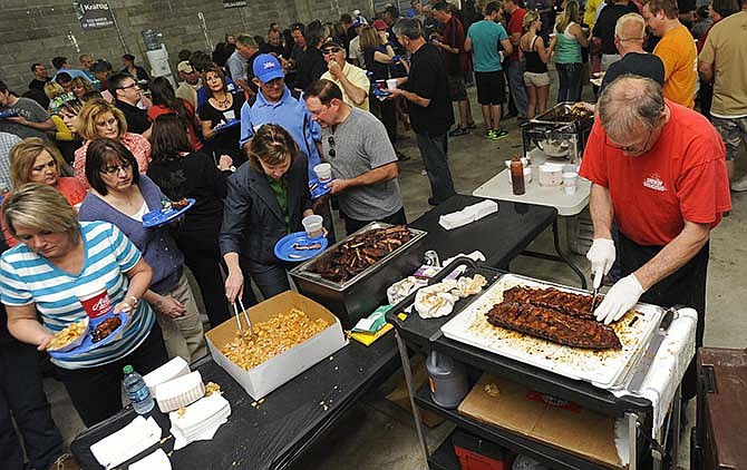 In this News Tribune file photo, Lutz's BBQ owner Burl Lutz goes to work slicing up racks of ribs as the crowd continues to grow at his station during the 2014 Capital City Cook-Off Buck-A-Bone BBQ Rib Competition at the Jefferson City Jaycees Fairgrounds.