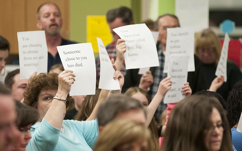 Parents and students attending the Fulton Public Schools Board of Education meeting Tuesday raise signs with statements included in the controversial "Claim It" activity conducted during a physical education class at Fulton Middle School.