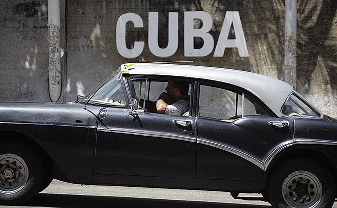 A man drives his taxi Tuesday past a Cultural Center with the word "Cuba" on it, in Havana, Cuba. President Barack Obama will remove Cuba from the list of state sponsors of terrorism, the White House announced Tuesday, a key step in his bid to normalize relations between the two countries. 