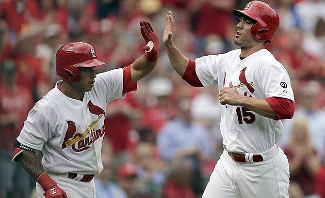 St. Louis Cardinals' Randal Grichuk, right, is congratulated by teammate Kolten Wong after scoring on a single by Yadier Molina during the eighth inning of a baseball game against the Milwaukee Brewers Thursday, April 16, 2015, in St. Louis.