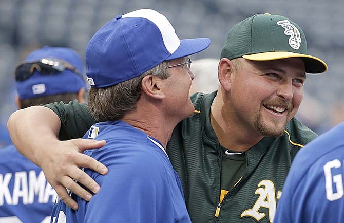 Longtime former Royal Oakland Athletics designated hitter Billy Butler, right, greets Kansas City Royals third base coach Mike Jirschele before a baseball game Friday, April 17, 2015, in Kansas City, Mo. 
