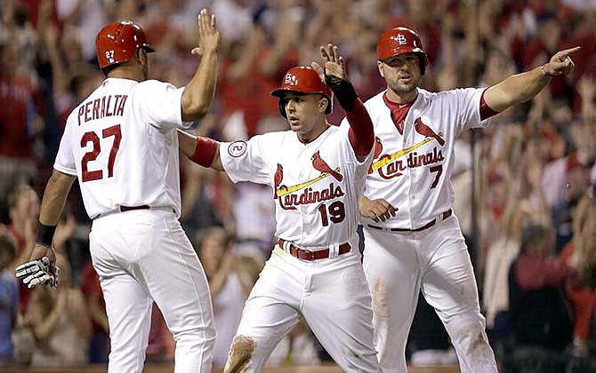 St. Louis Cardinals' Jhonny Peralta, left, Jon Jay, center, and Matt Holliday, right, celebrate after scoring on a double by Yadier Molina during the seventh inning of a baseball game against the Cincinnati Reds Friday, April 17, 2015, in St. Louis.