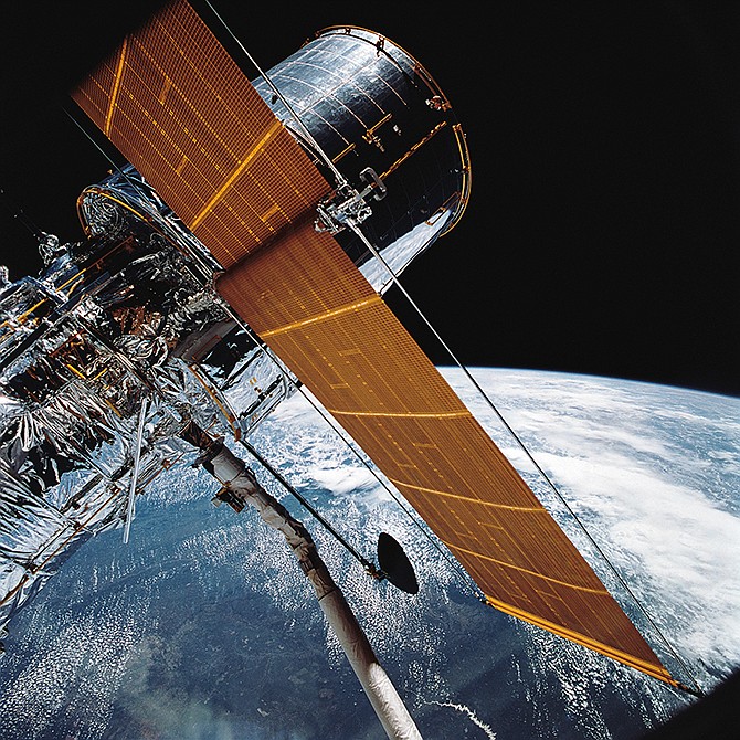 In this April 25, 1990, NASA photograph, most of the giant Hubble Space Telescope can be seen as it is suspended in space by Discovery's Remote Manipulator System following the deployment of part of its solar panels and antennae. This was among the first photos NASA released on April 30 from the five-day STS-31 mission.