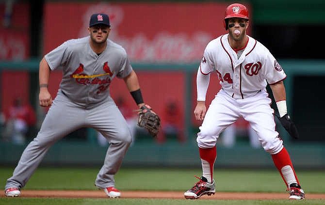 Washington Nationals' Bryce Harper, right, takes a lead off of first base while blowing a bubble as St. Louis Cardinals first baseman Matt Adams, left, looks on during the first inning of a baseball game, Thursday, April 23, 2015, in Washington.