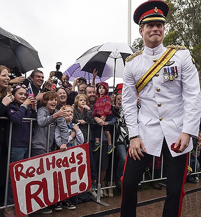 Prince Harry, right, reacts after shaking hands with kids holding up a sign reading "Red Heads Rule" during a visit to the Australian War Memorial in Canberra, Australia. Harry, the second son of Prince Charles and Diana, is often seen as the mischievous one, the fun-loving counterpart to the more staid - some say dull - William.