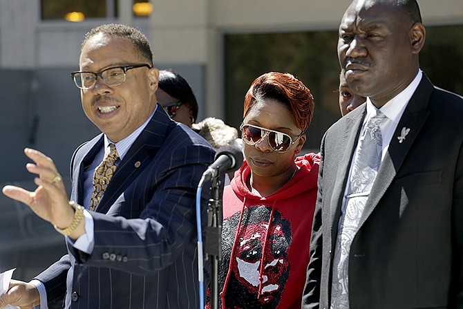 Lesley McSpadden, the mother of Michael Brown, listens alongside attorneys Anthony D. Gray, left, and Benjamin L. Crump, right, during a news conference Thursday in Clayton. The parents of Michael Brown filed a wrongful-death lawsuit against the city of Ferguson over the fatal shooting of their son by a white police officer.