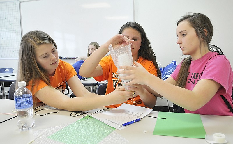 Thomas Jefferson Middle School eighth-grade students, from left, Maddie Jones, Trinity Pendleton and Morgan Surls work together to make a container in which they can house an egg to prevent it from breaking after a drop from a third-floor window Friday during the 11th Annual Lincoln University Math for Girls Day.