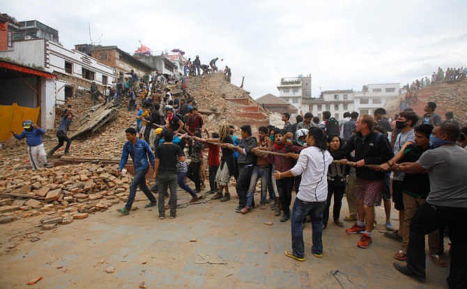 Volunteers help remove debris of a building that collapsed at Durbar Square, after an earthquake in Kathmandu, Nepal, Saturday, April 25, 2015. A strong magnitude-7.9 earthquake shook Nepal's capital and the densely populated Kathmandu Valley before noon Saturday, causing extensive damage with toppled walls and collapsed buildings, officials said. 