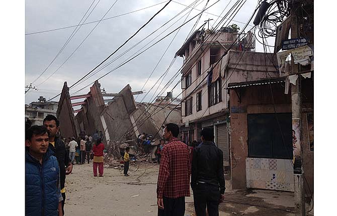 In this photo provided by Guna Raj Luitel, people walk next to ruble after an earthquake in Kathmandu, Nepal, Saturday, April 25, 2015. A powerful earthquake shook Nepal's capital and the densely populated Kathmandu Valley before noon Saturday, collapsing houses, leveling centuries-old temples and cutting open roads in the worst temblor in the Himalayan nation in over 80 years.