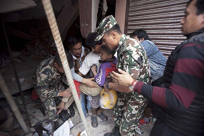 Volunteers carry an injured boy after rescuing him from the debris of a building that was damaged in an earthquake in Kathmandu, Nepal, Saturday, April 25, 2015. A strong magnitude-7.9 earthquake shook Nepal's capital and the densely populated Kathmandu Valley before noon Saturday, causing extensive damage with toppled walls and collapsed buildings, officials said. 