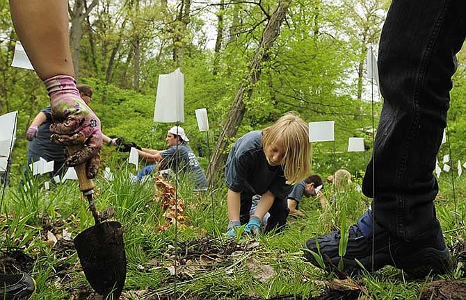 Volunteers of all ages, including Elizabeth Fetes, center, and a number of her fellow Girl Scouts
from Troop 71062 of West Elementary School help plant river oats along the creek bank at Jefferson City's Memorial
Park as part of Saturday's annual Serve Jeff City event.