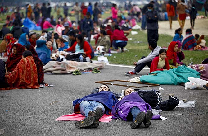 In this photo provided by China's Xinhua News Agency, tourists sleep at an open space after an earthquake in Kathmandu, Nepal, Sunday, April 26, 2015. Planeloads of aid material, doctors and relief workers from neighboring countries began arriving Sunday in Nepal, a poor Himalayan nation reeling from a powerful earthquake that destroyed infrastructure, homes and historical buildings. 