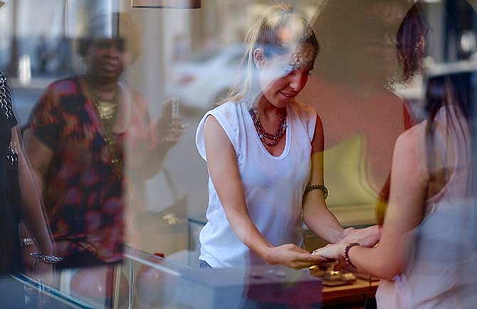In this April 2, 2015 photo, a shopper tries on rings at a luxury jewelry shop in Beverly Hills, Calif. The Conference Board released the Consumer Confidence Index for April on Tuesday, April 28, 2015.