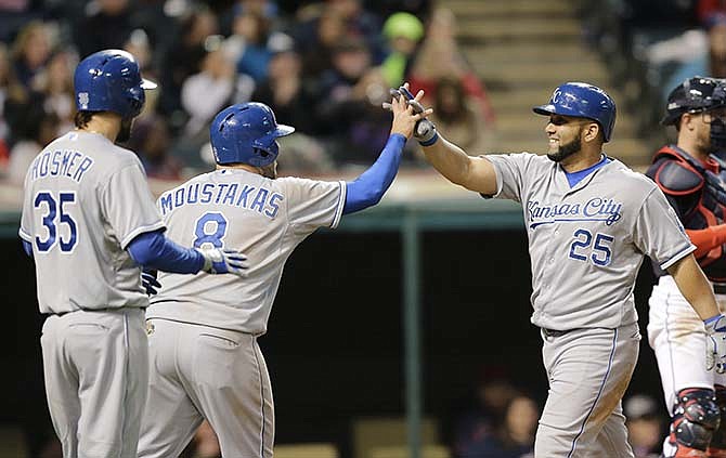 Kansas City Royals' Kendrys Morales (25) is congratulated by Mike Moustakas (8) and Eric Hosmer (35) after Morales hit a three-run home run off Cleveland Indians relief pitcher Bryan Shaw in the seventh inning of a baseball game, Tuesday, April 28, 2015, in Cleveland. All three scored on the play.