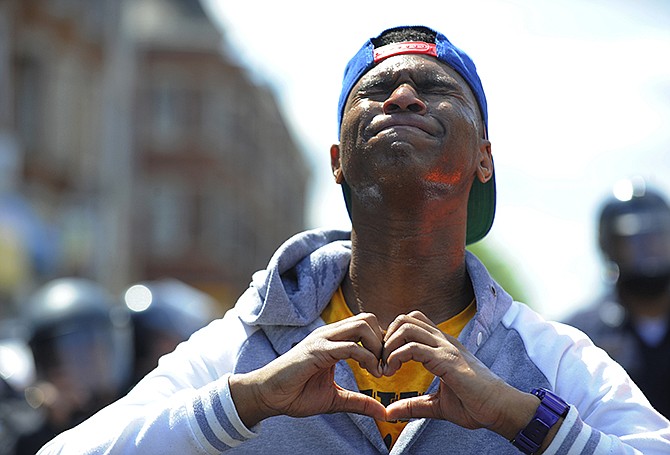 Devante Hill makes a heart with his hands after he was hit with pepper spray during a protest in Baltimore on Tuesday.
