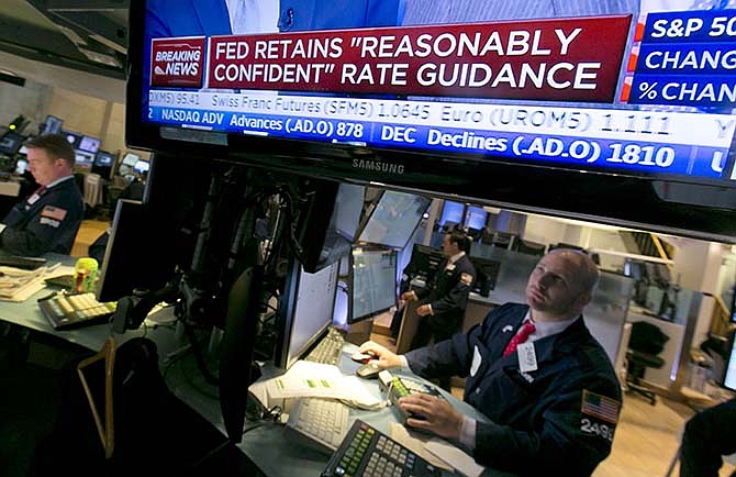 Specialist John Parisi, left, looks toward a television screen that shows the decision of the Federal Reserve, on the floor of the New York Stock Exchange, Wednesday, April 29, 2015. The Federal Reserve has downgraded its assessment of the economy after a winter in which growth nearly stopped. The Fed offered no sign that a rate increase might be coming soon.