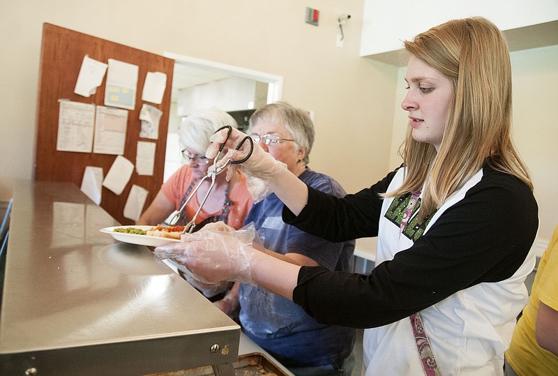 Madison Murphy, a member of Southside Baptist Church, places bread on a plate Thursday inside the John C. Harris Community Center during Fulton Soup Kitchen hours. The soup kitchen is extending its days to include Fridays, starting on May 8, and is seeking more volunteers to cover Monday-Friday shifts.