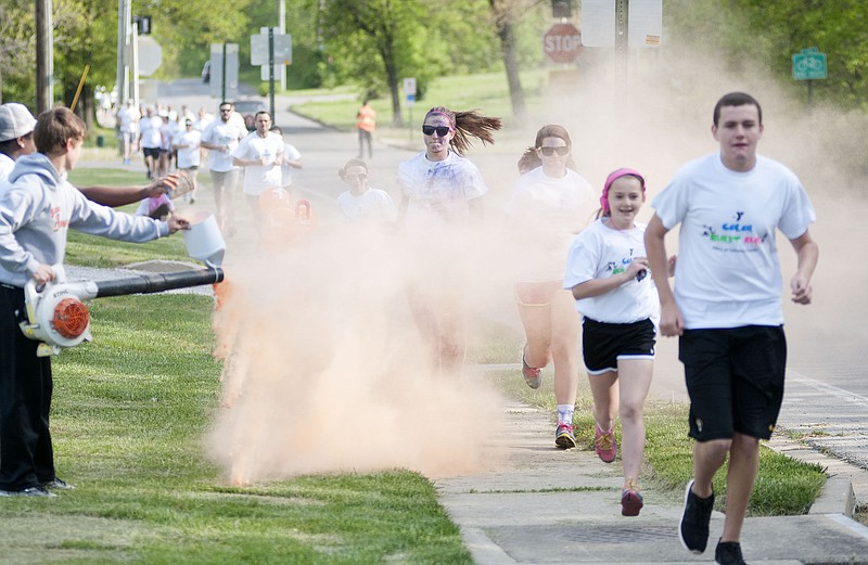 Runners race through the first color station on Wood Street Saturday during the YMCA of Callaway County Color Burst 5K. 