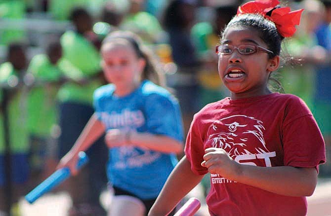  A member of an East Elementary relay team heads down the track after receiving the baton Saturday during the Little Olympics at Adkins Stadium in Jefferson City.

