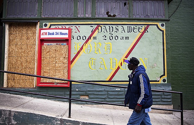 A man walks past the damaged Oxford Tavern Thursday in Baltimore. In a presidential campaign where candidates are jockeying to be champions of the middle class and courting donations from the wealthy, the poor are inching their way into the debate.