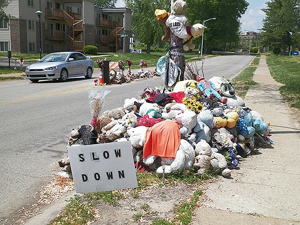 A car passes two makeshift memorials Tuesday to Michael Brown near where the unarmed, black 18-year-old was shot and killed last August. The city is thinking about moving the memorial.