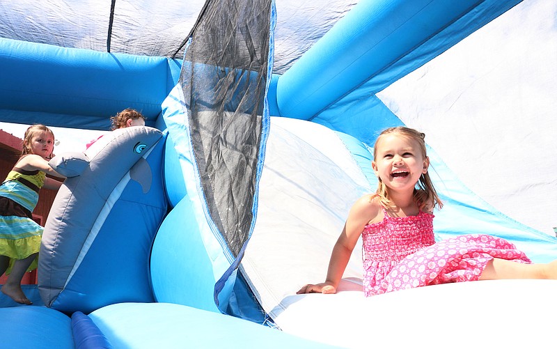 Macy Fletchall, 4, laughs after sliding down a slide in a bounce house at Memorial Park Thursday afternoon. Socket, a Missouri-based telephone and Internet service provider, brought the bounce house to the park and gave out free food in celebration of the company making the Fulton park a free Wi-Fi hotspot.