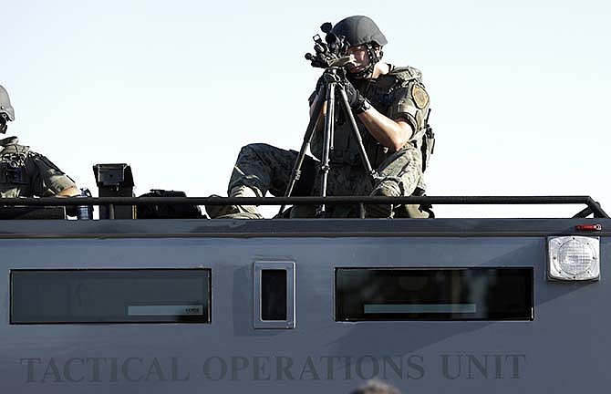 In this Aug. 13, 2014 file photo, a member of the St. Louis County Police Department trains his weapon on a relatively small group of protesters in Ferguson, Mo. Two Democratic members of Missouri's congressional delegation said Thursday, May 7, 2015, they're seeking to reform federal programs that provide military equipment to police, responding to allegations that local law enforcement overreached by using armored vehicles and high-caliber weapons during Ferguson protests. U.S. Sen. Claire McCaskill introduced the Protecting Communities and Police Act on Thursday, and U.S. Rep. William Lacy Clay plans to propose a companion version next week. It would create a task force to determine what sort of equipment is suitable for police and what should be prohibited. 