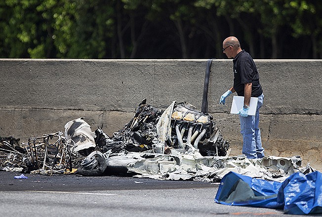 An investigator looks at the wreckage of a plane that crashed Friday killing all four people aboard and starting an intense fire on ton Interstate 285, in Doraville, Gerorgia. 