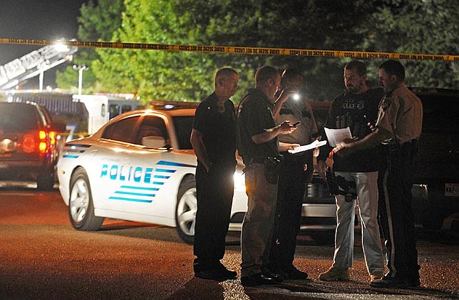 Hattiesburg lawmen study information on suspects wanted for the fatal shooting of two Hattiesburg, Miss., police officers, Saturday night, May 9, 2015. Authorities are conducting a manhunt for the suspects. (Ryan Moore/WDAM-TV via AP)
