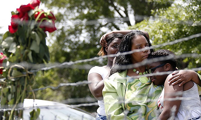 Area residents Alberta Harris, center, and Waynetta Theodore, left, and Christiena Preston, console each other as they pay their respects at a makeshift memorial near the site where two Mississippi police officers were killed Sunday in Hattiesburg, Mississippi. 
