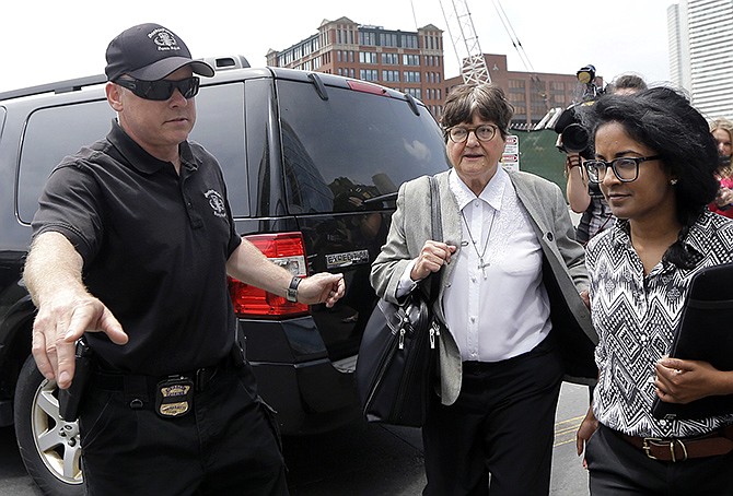 A member of the Boston Police Bomb Squad points the way for death penalty opponent Sister Helen Prejean, center, Monday as she departs federal court in Boston after testifying during the penalty phase in Dzhokhar Tsarnaev's trial.