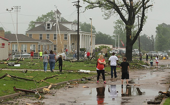Dozens of Van, Texas, residents walk around the intermediate and elementary schools' campuses as they survey the damage from Monday's severe weather that moved through the area in the early morning hours. 