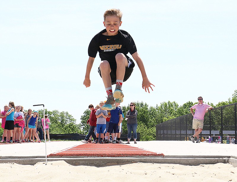 A South Callaway elementary student prepares to land in a sand pit during the long jump at the school's field day Tuesday.