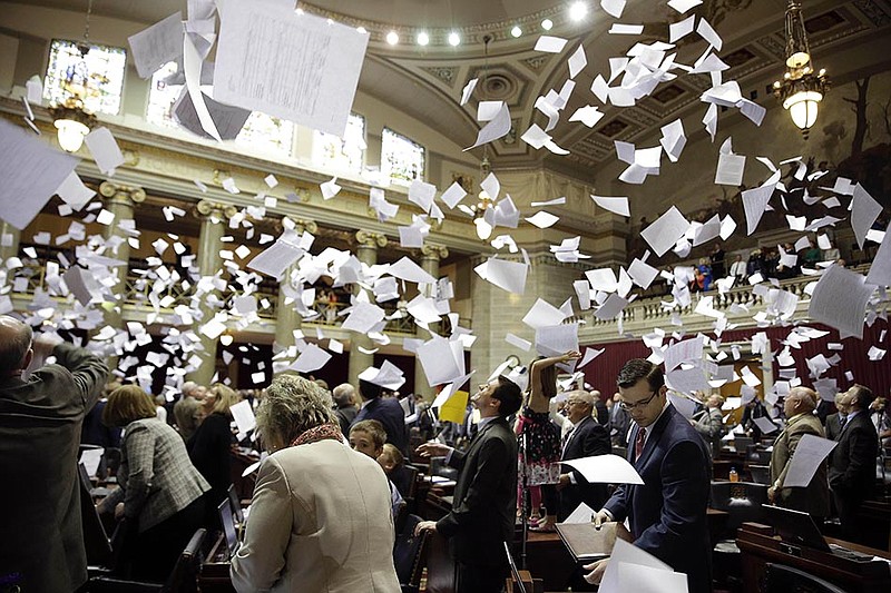 Members of the Missouri House of Representatives throw papers in the air Friday at the conclusion of the legislative session at the Capitol.