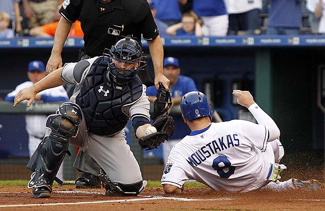 Kansas City Royals' Mike Moustakas (8) scores from second base as New York Yankees catcher Brian McCann catches a late throw during the first inning of a baseball game at Kauffman Stadium in Kansas City, Mo., Friday, May 15, 2015. Moustakas scored on a Lorenzo Cain double.