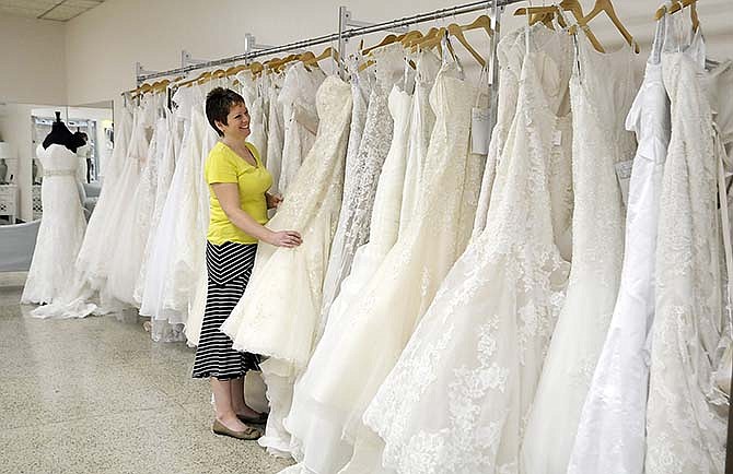 Wendy Gladbach, owner of Ana Marie's Bridal in downtown Jefferson City, straightens out
wedding gowns hanging on the rack.