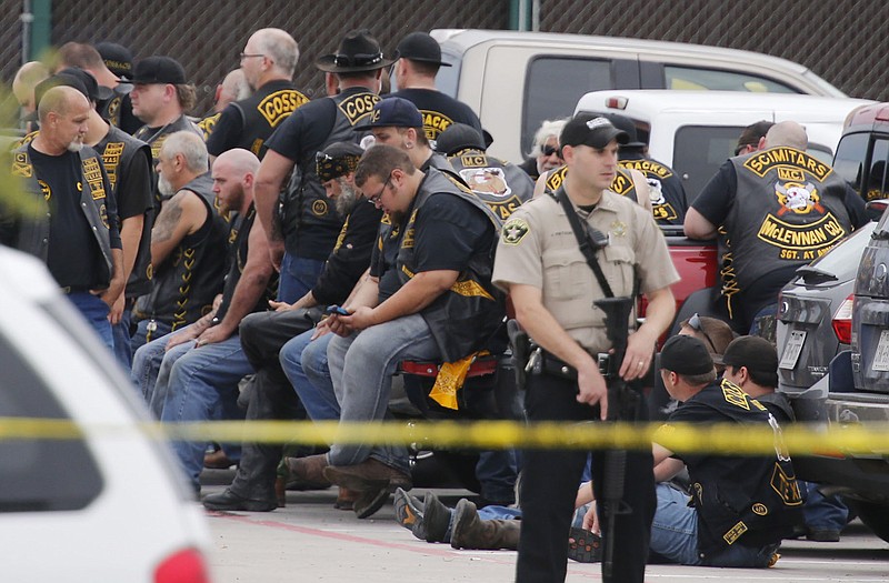 A McLennan County deputy stands guard near a group of bikers in the parking lot of a Twin Peaks restaurant Sunday in Waco, Texas.
