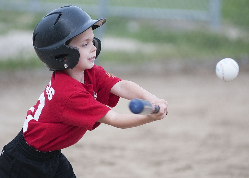 A young boy swings during a tee-ball game on Tuesday at Howard Field in Holts Summit. The boy plays for a team sponsored by Generations Childcare in Holts Summit. The Holts Summit Optimist Club sponsors the youth league.