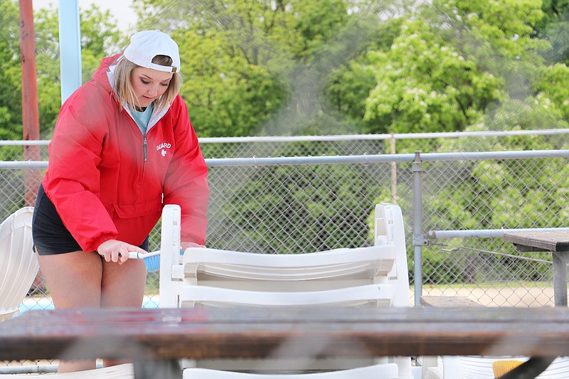 New Bloomfield High School student Alyssa Bradley cleans off patio chairs at Fulton's pool Wednesday in preparation for its opening day Saturday.