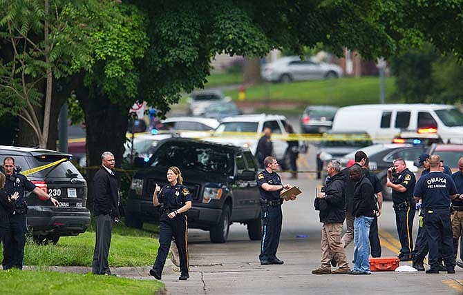 Law enforcement officers gather near the scene of a shooting Wednesday, May 20, 2015 in Omaha, Neb. Police say one female officer and at least one other person were shot and are being treated at an Omaha hospital. (Chris Machian/Omaha World-Herald via AP)