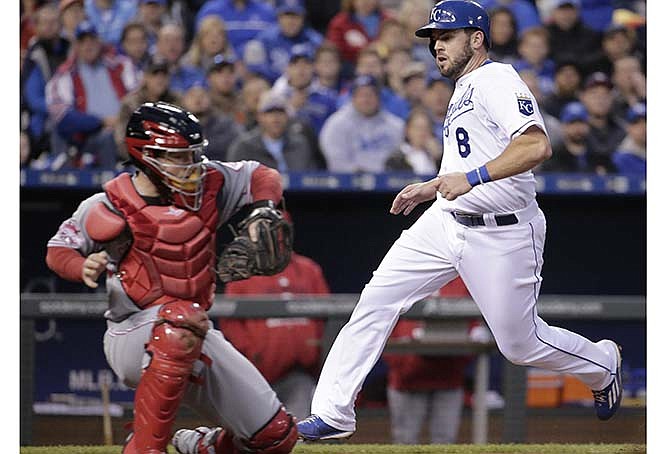 Kansas City Royals' Mike Moustakas runs past Cincinnati Reds catcher Tucker Barnhart to score on a fielders choice hit into by Eric Hosmer during the fourth inning of a baseball game Wednesday, May 20, 2015, in Kansas City, Mo.